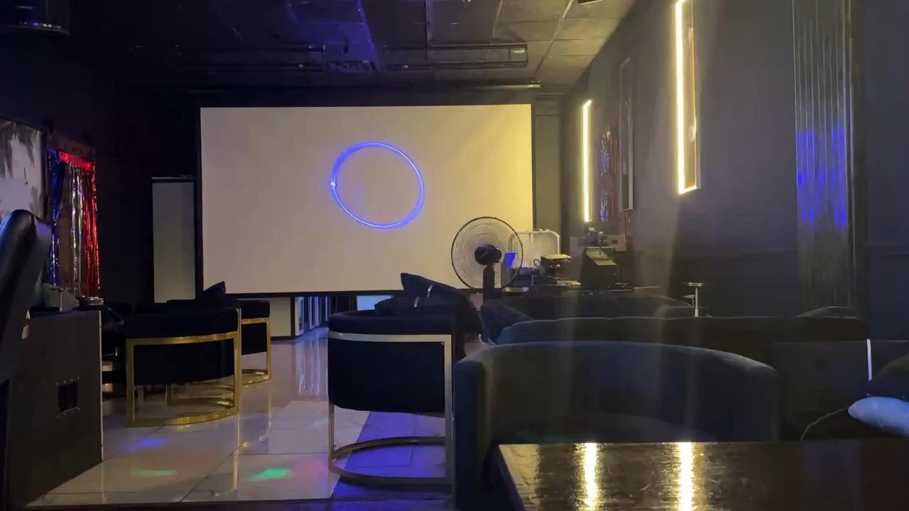 A pan across the main floor toward the projection screen, with coloured light moving over the marble and the lounge seating.
